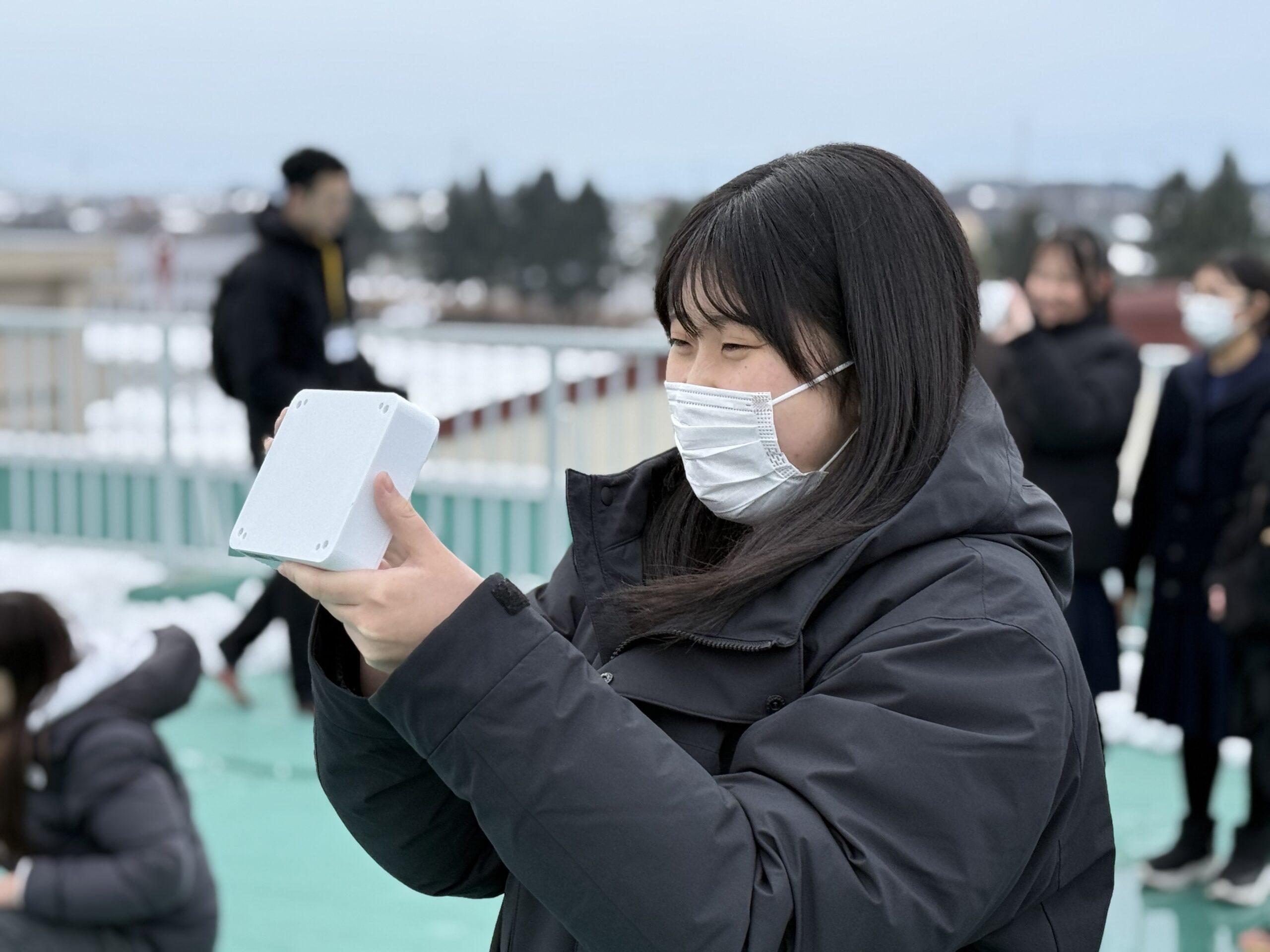 送信実験で高校生が通信機をYODAKAに向ける様子 ※無線局の技術操作は無線従事者が実施